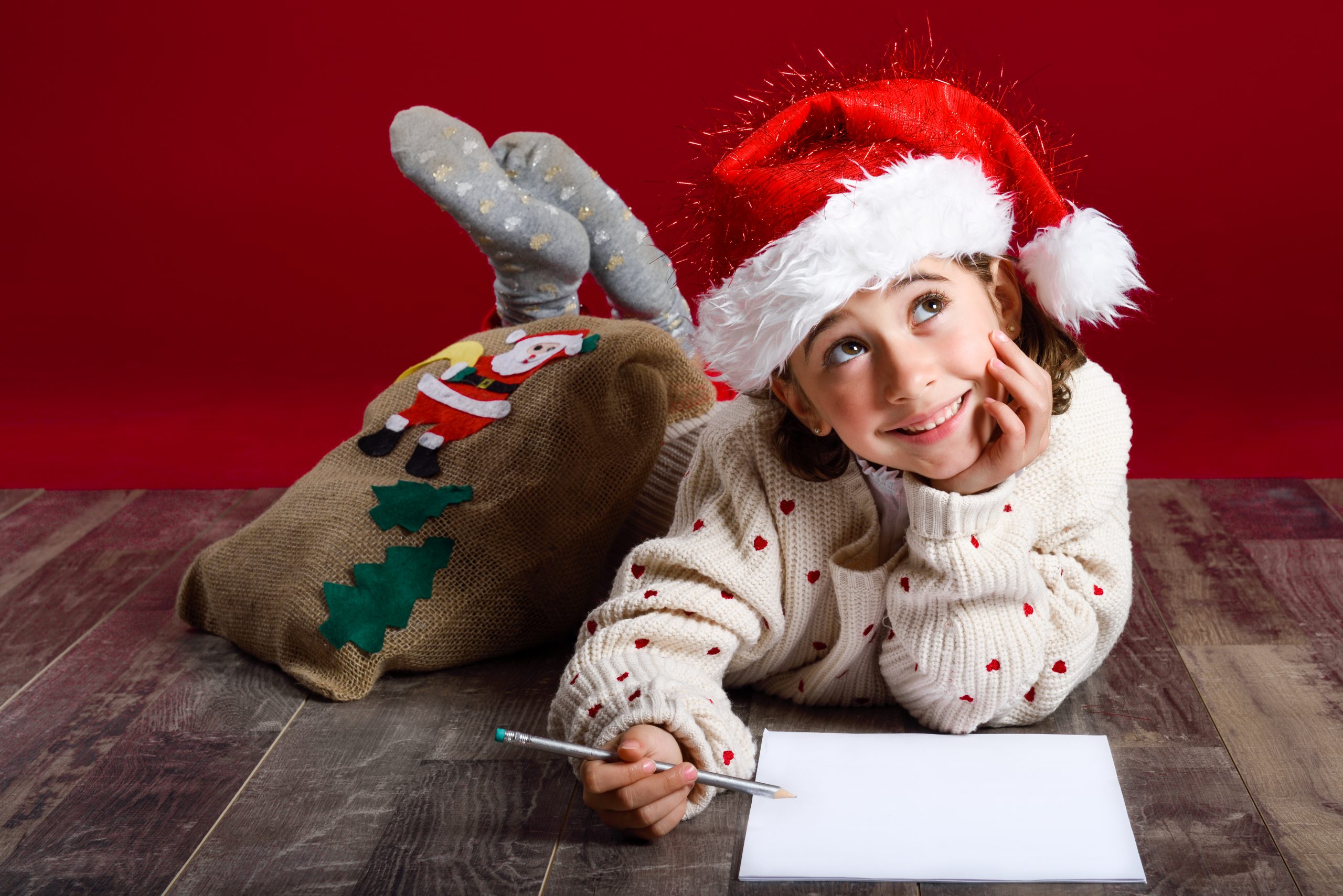 niña pinta postal navideña Adorable little girl wearing santa hat writing Santa letter on wooden floor. Winter clothes for Christmas.