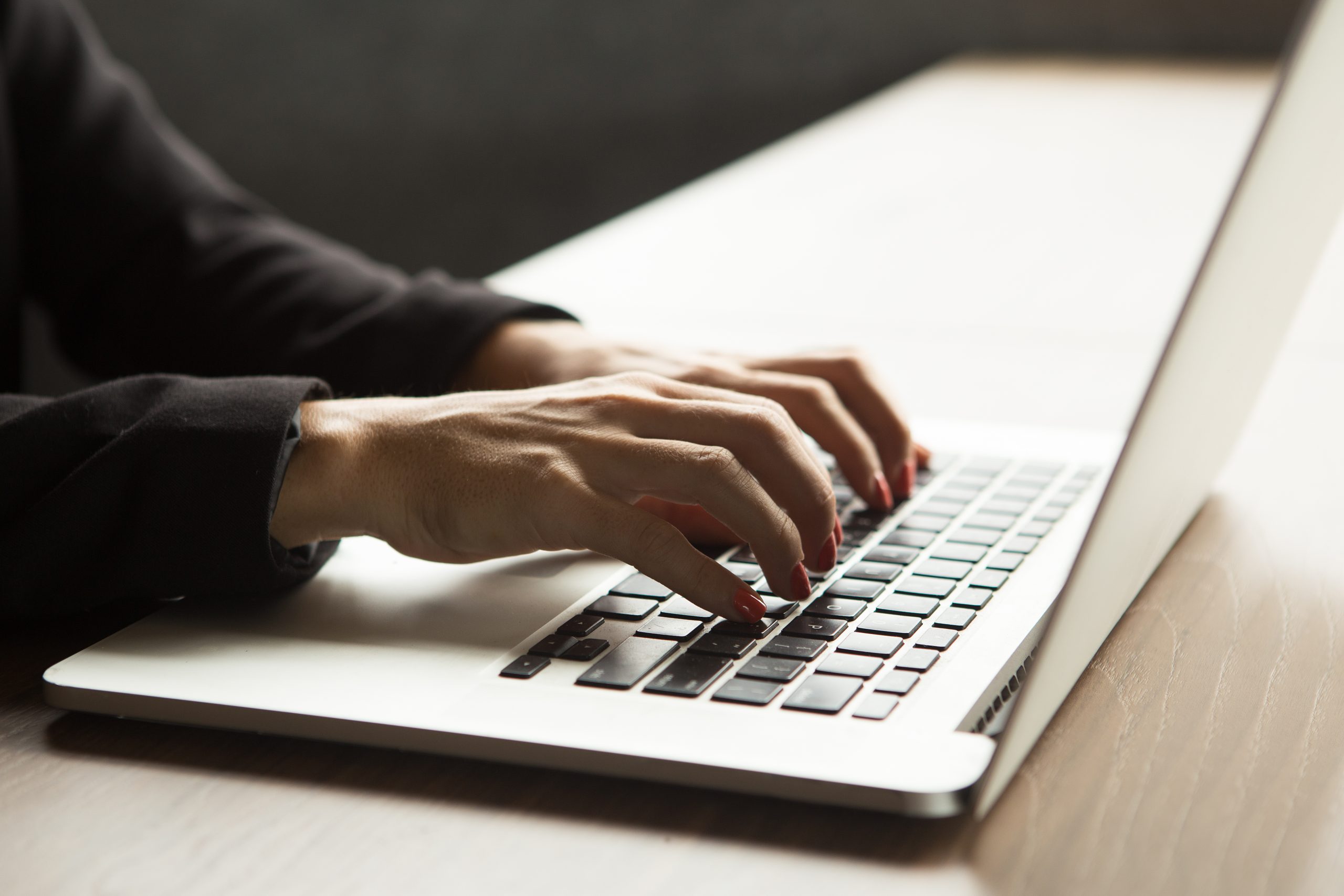 Close-up of female hands typing on laptop at table. Businesswoman working in office