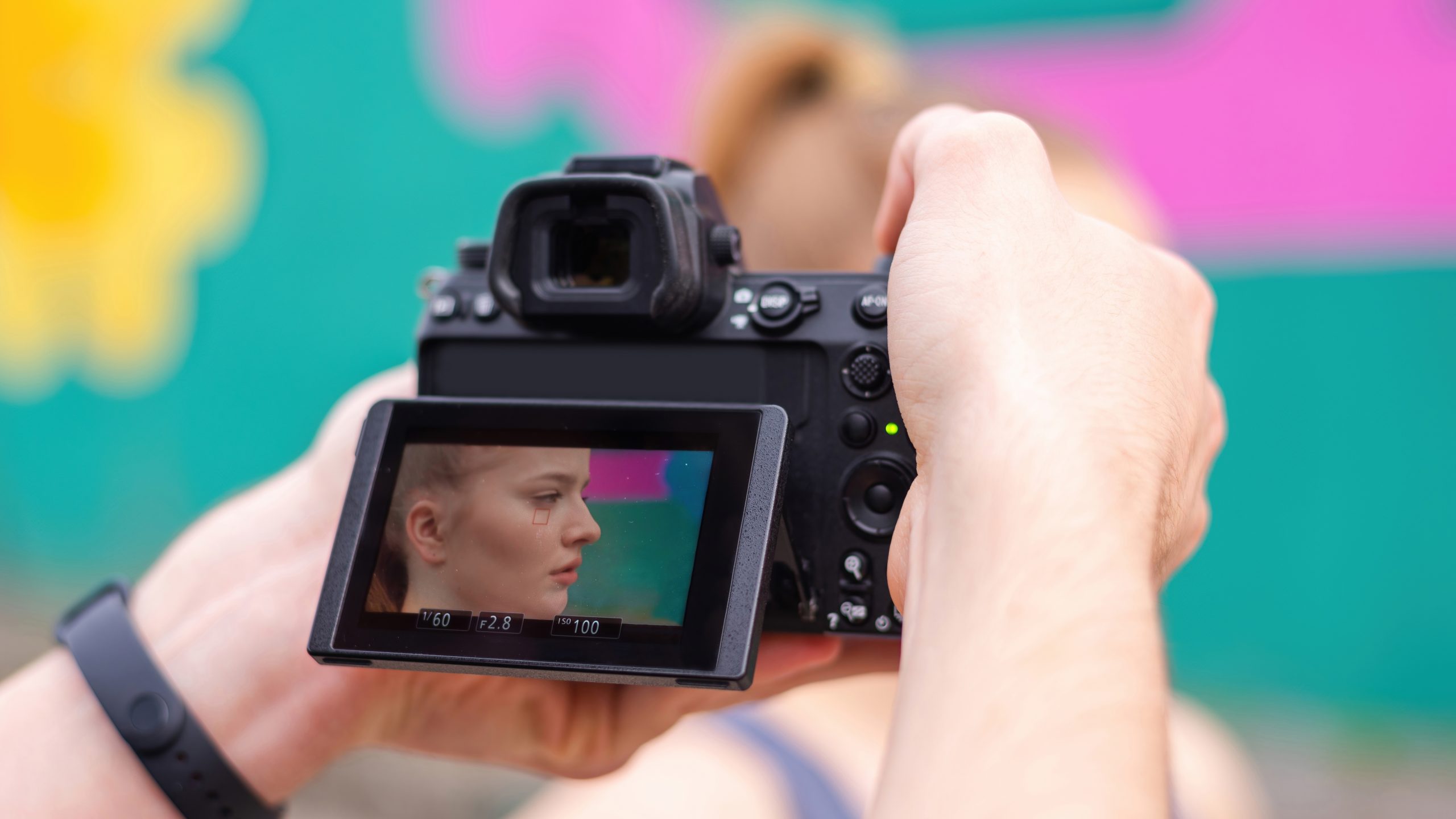Photographer taking shot of a young blonde woman in sportswear at outdoors training, multicolored background