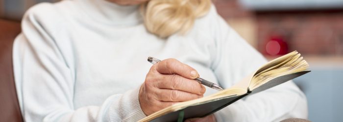 close-up-senior-mujer-escribiendo-en-agenda