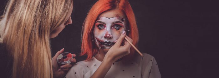 Talented makeup artist is creating special scary Halloween art on woman's face.