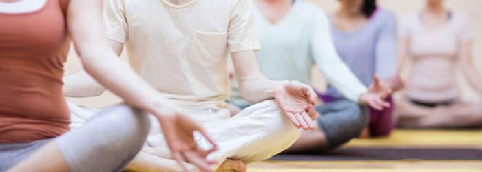 Group of people sitting in lotus position in the fitness studio