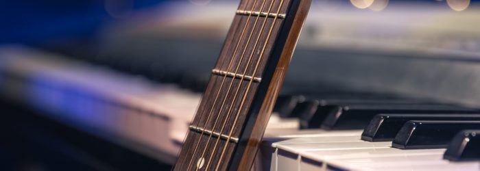 Guitar and piano keys close-up on a blurred background with bokeh, musical holiday background.