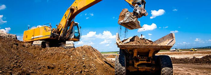 Industrial truck loader excavator moving earth and unloading into a dumper truck