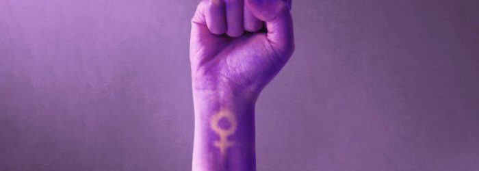 Raised purple fist of a woman for international women's day and the feminist movement. March 8 for feminism, independence, freedom, empowerment, and activism for women rights