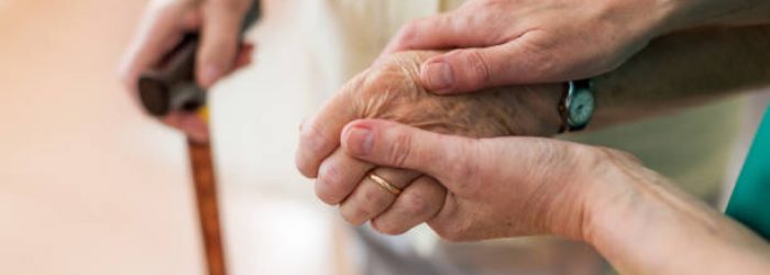 Nurse consoling her elderly patient by holding her hands