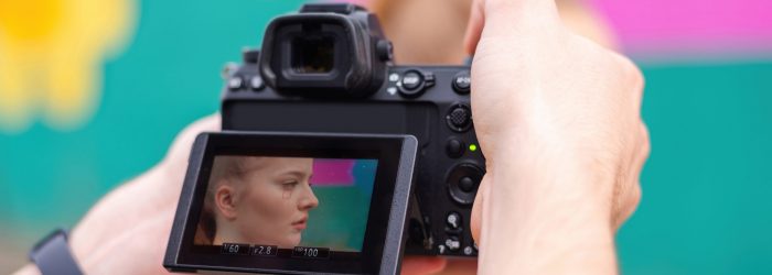 Photographer taking shot of a young blonde woman in sportswear at outdoors training, multicolored background