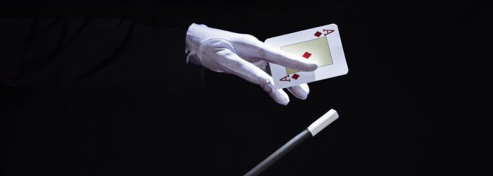 primer-plano-de-mago-realizando-truco-en-naipes-con-varita-magica